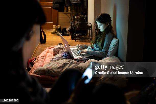 Girl sits with a laptop in the corridor of an apartment hiding during a Russian missile attack on January 2, 2024 in Kyiv, Ukraine.