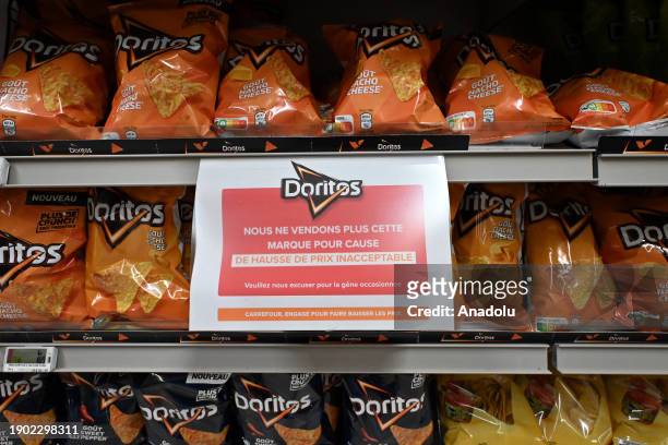 Sign reading in French in a Carrefour on a shelf for the PepsiCo product Doritos' reads: 'We no longer sell this brand due to unacceptable price...