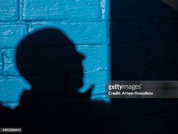 profile view of man, on blue brick wall - profile silhouette stock pictures, royalty-free photos & images