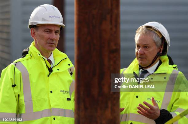 Britain's Chancellor of the Exchequer Jeremy Hunt talks with Openreach CEO Clive Selley as he is shown a demonstration of how to safely climb a...