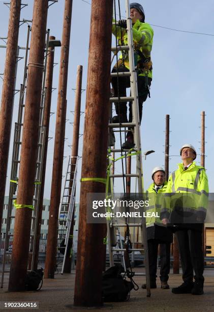 Britain's Chancellor of the Exchequer Jeremy Hunt talks with Openreach CEO Clive Selley as he is shown a demonstration of how to safely climb a...