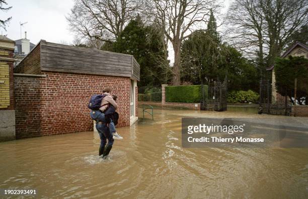 Man carries a woman on his back to keep her dry on the 'Rue Leon Blum' on January 4, 2024 in Blendecques, Pas-de-Calais, France. A state of danger...