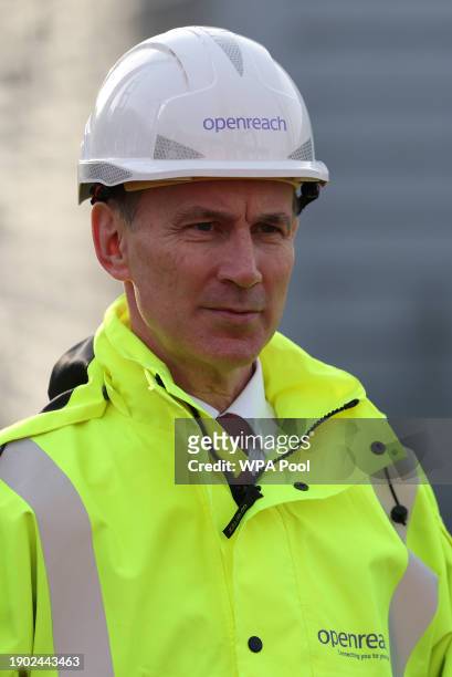 Britain's Chancellor of the Exchequer Jeremy Hunt reacts as he is shown a demonstration of how to safely climb a telephone pole during a visit to...