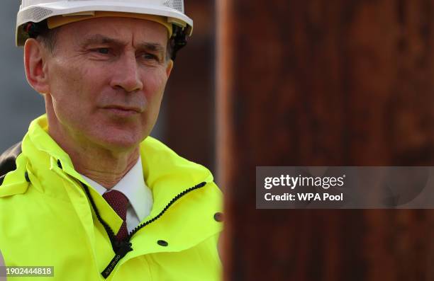 Britain's Chancellor of the Exchequer Jeremy Hunt reacts as he is shown a demonstration of how to safely climb a telephone pole during a visit to...