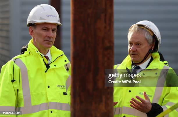 Britain's Chancellor of the Exchequer Jeremy Hunt talks with Openreach CEO Clive Selley as he is shown a demonstration of how to safely climb a...