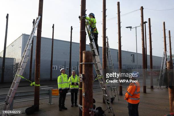 Britain's Chancellor of the Exchequer Jeremy Hunt talks with Openreach CEO Clive Selley as he is shown a demonstration of how to safely climb a...