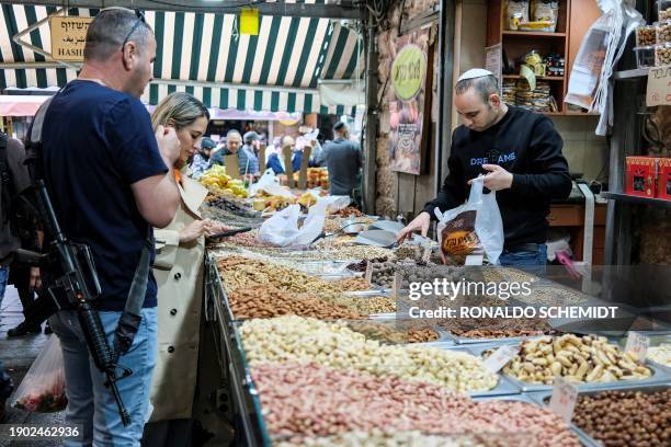 Customers shop at a stall at Jerusalem's Mahane Yehuda market, on January 5, 2024.
