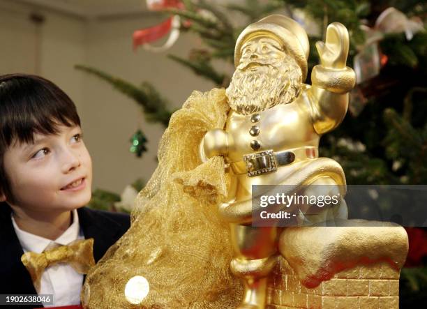 Boy gazes at a gold Santa Claus statue, 41 cm tall, weighing 20kg and priced at 200 million yen , at Tanaka Kikinzoku Jewelry shop in Tokyo, 20...