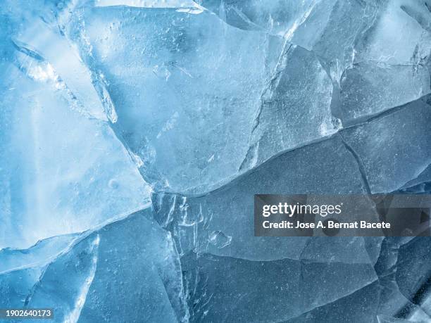 full frame, frozen water surface in a river with cracks and broken ice crystals of turquoise blue color. - glace texture imagens e fotografias de stock