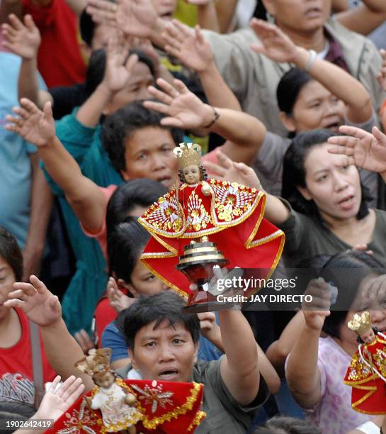 Devotees, attending a mass, raise their hands in prayer as they hold a religious icon of the Santo Niño, at the Basilica Del Santo Niño in Cebu city,...