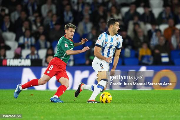 Mikel Merino of Real Sociedad runs with the ball whilst under pressure from Antonio Blanco of Deportivo Alaves during the LaLiga EA Sports match...