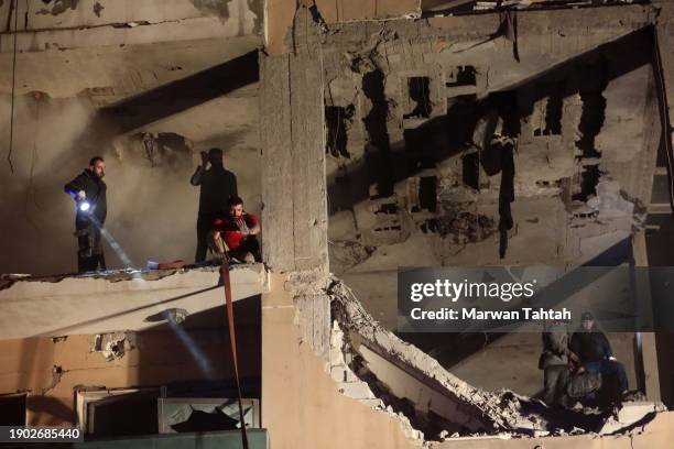 Firefighters and civil defense are seen in a damaged building that was allegedly targeted by an Israeli drone strike on January 2, 2024 in Dahiyeh, a...