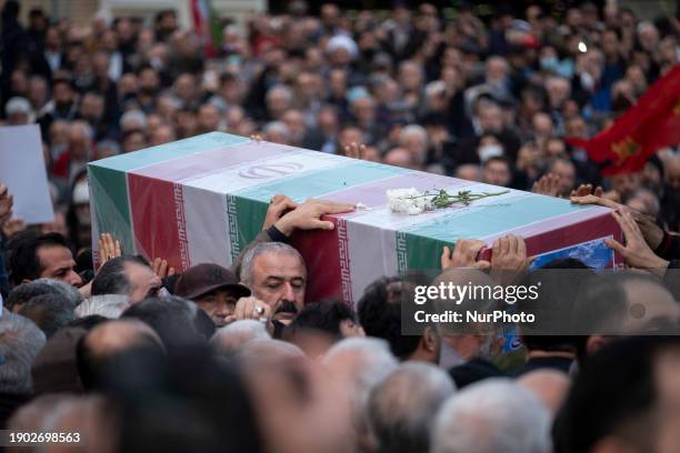 Iranian worshippers are carrying a coffin containing the body of Faezeh Rahimi, who was killed in attacks in Kerman, during an anniversary ceremony...