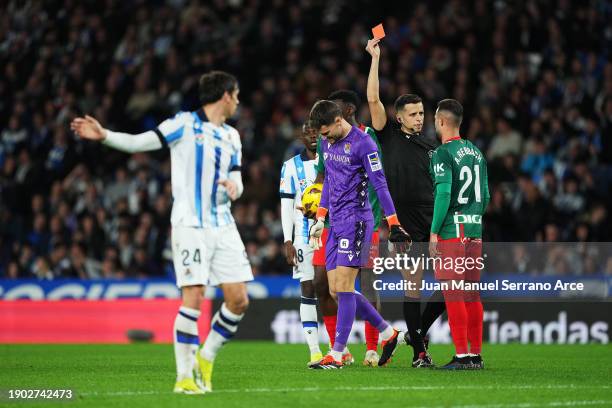 Abde Rebbach of Deportivo Alaves speaks with Referee Victor Garcia Verdura as he shows a red card to Alejandro Remiro of Real Sociedad during the...