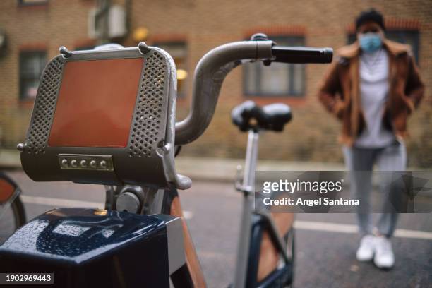 man in mask approaching public bike rental - commuter man europe bike stock pictures, royalty-free photos & images