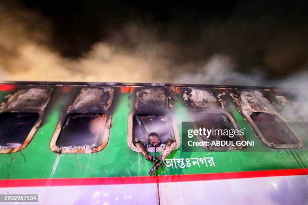 Graphic content / The remains of a passenger trying to escape a deadly train fire is seen hanging from a window of a burnt out carriage of the...