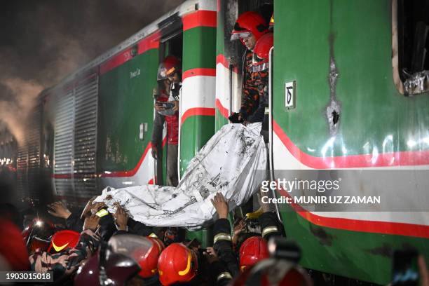 Graphic content / Rescue personnel remove the remains of body from a burnt out carriage of the Benapole Express in Dhaka on January 5, 2024. Five...