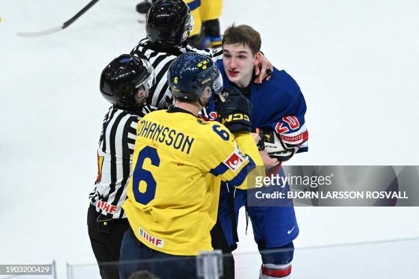 Sweden's defender Anton Johansson and USA's defender Lane Hutson are seperated by referees during the final ice hockey match between USA and Sweden...