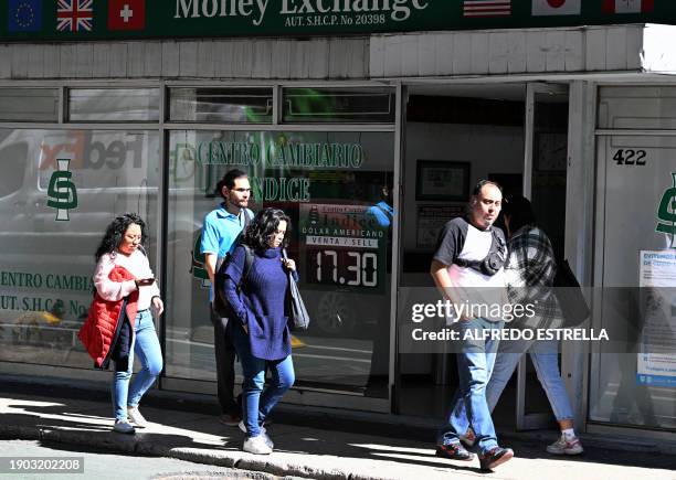 People pass by an exchange house at Reforma Avenue in Mexico City on January 5, 2024. In recent weeks, the Mexican peso has strengthened against the...