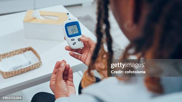 young adult woman doing a glucose blood test at home - blood sugar test stock pictures, royalty-free photos & images