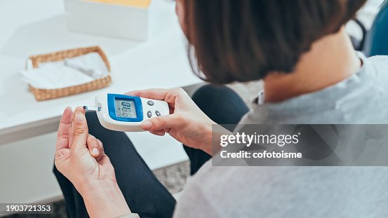 Young adult Woman doing a glucose blood test at home Young adult Woman doing a glucose blood test at home