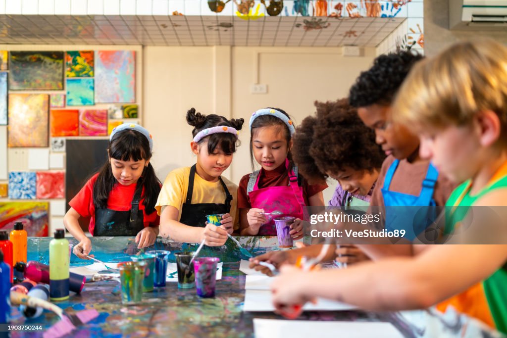 Group of Diversity school children learning acrylic art together in art class.