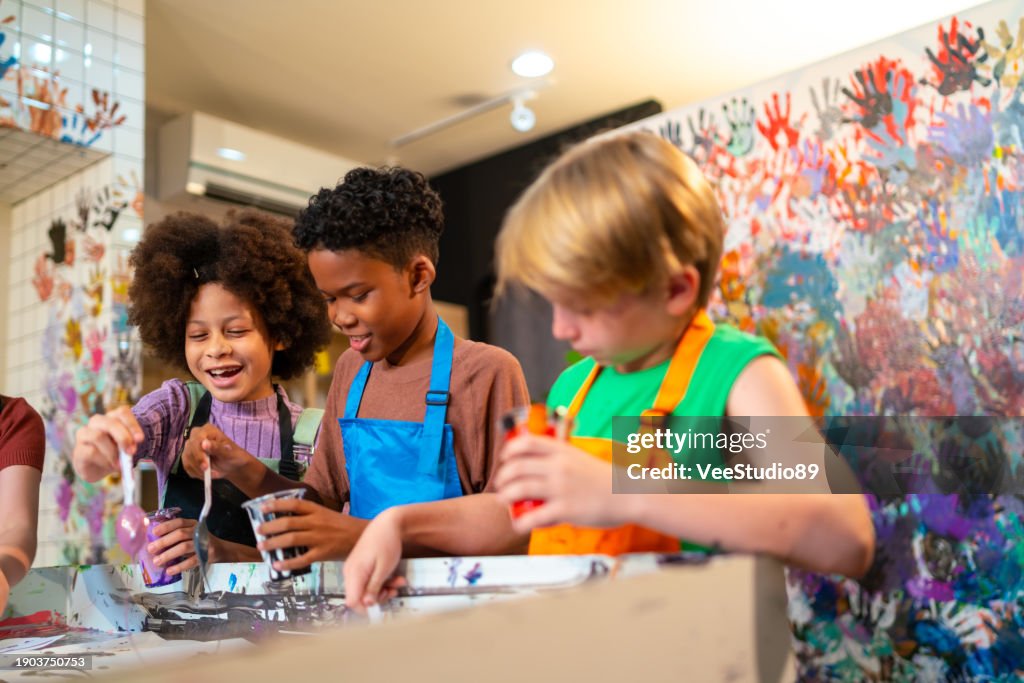 Group of Diversity school children learning acrylic art together in art class.
