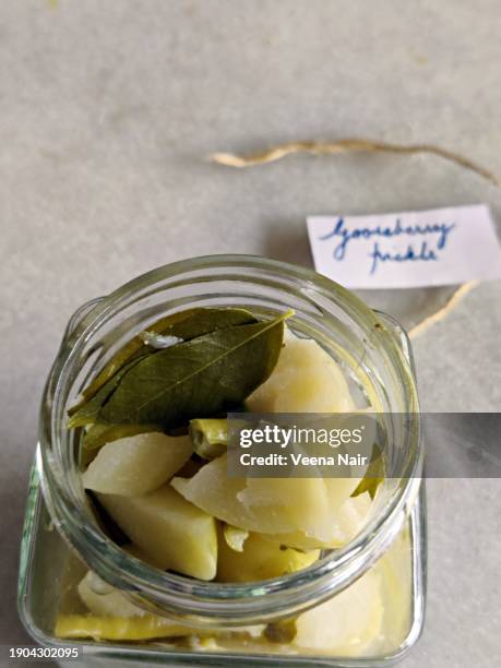 raw gooseberry/amla pickle with green chili, curry leaf and ginger in a glass jar/handwritten tag/still life - amla pickle stock pictures, royalty-free photos & images