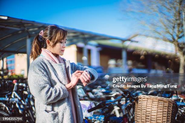 beautiful asian business woman using smart watch after parking her bicycle in cycle park outside the train station - bike basket stock pictures, royalty-free photos & images