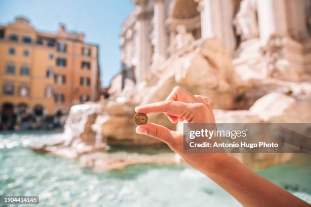 woman's hand holding a coin at the trevi fountain in rome, italy. - coin fountain imagens e fotografias de stock