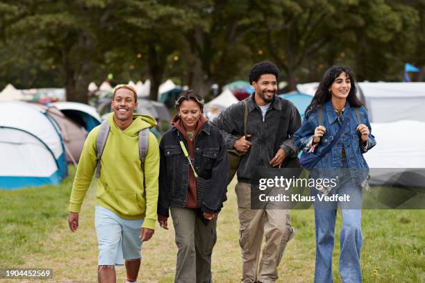smiling friends walking together against tents - sac bandoulière photos et images de collection