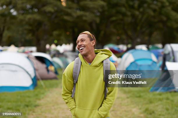 cheerful man with hands in pockets against tents - sweatshirt stockfoto's en -beelden
