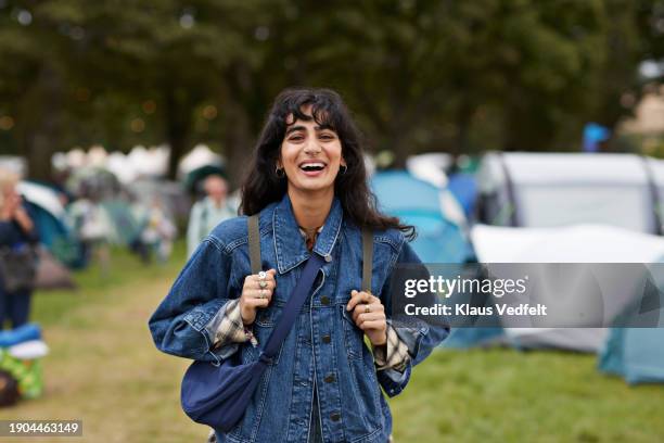 cheerful woman in denim jacket standing against tents - one mid adult woman only stock pictures, royalty-free photos & images