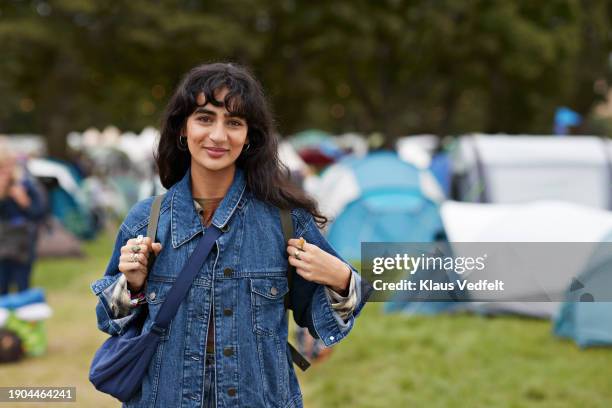 smiling woman in denim jacket standing against tents - one mid adult woman only stock pictures, royalty-free photos & images