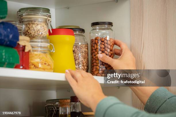 female hand picking glass container of food from kitchen cabinet - voorraadkast stockfoto's en -beelden