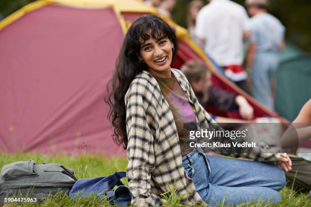 happy woman wearing checked shirt sitting on grass - one mid adult woman only stock pictures, royalty-free photos & images