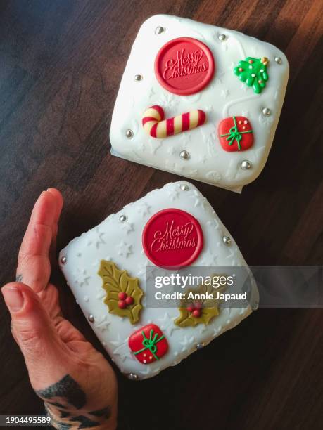 overhead view of a hand and two embossed christmas cakes set on wooden table - galway people stock pictures, royalty-free photos & images