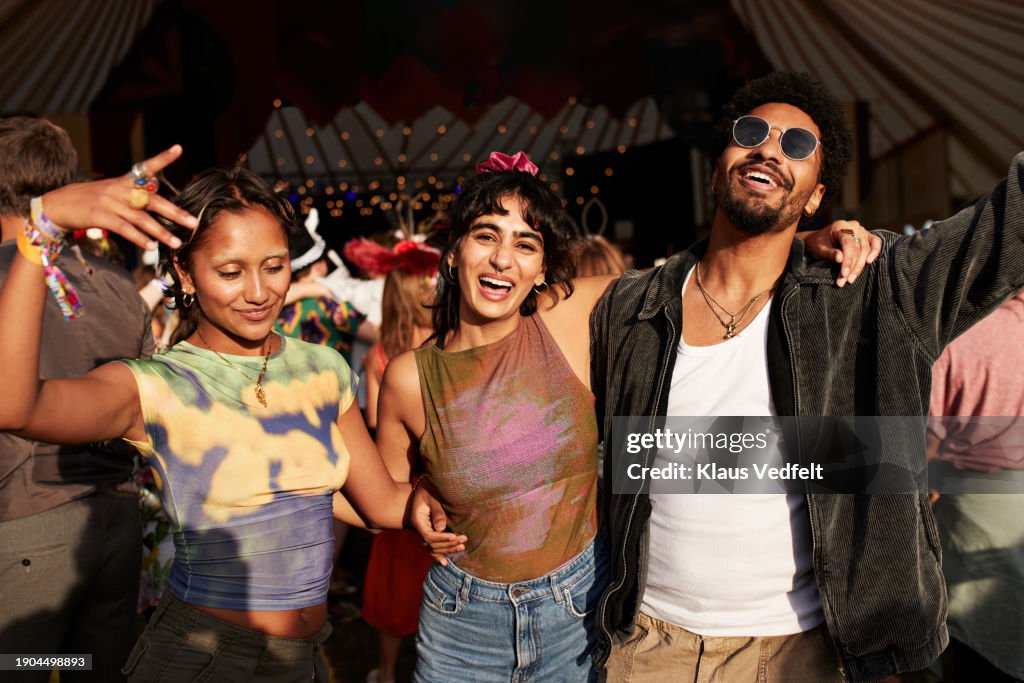 Cheerful woman dancing with arms around friends