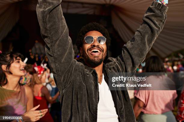 cheerful young man dancing with arms raised near girlfriend - livel music stock pictures, royalty-free photos & images