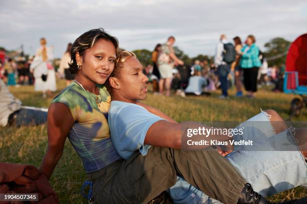 smiling young woman sitting on grass with boyfriend - music festival grass stock pictures, royalty-free photos & images