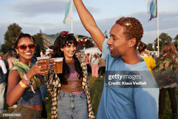 man with arm raised near friends holding beer - human arm stock pictures, royalty-free photos & images