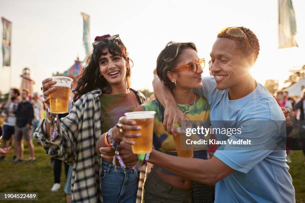 happy man with arm around girlfriend near friend - drinking beer festival stock-fotos und bilder