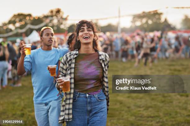 cheerful woman with beer walking at music festival - one mid adult woman only stock pictures, royalty-free photos & images