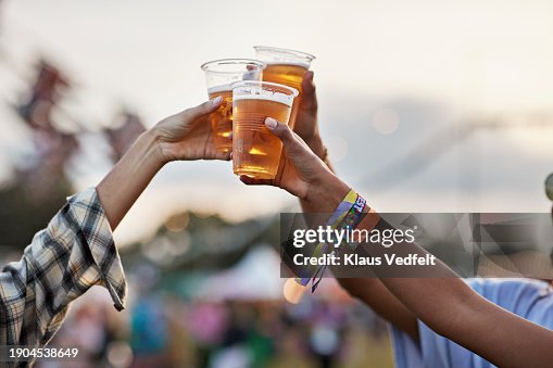 Hands of man and women toasting beer at music festival Hands of man and women toasting beer at music festival