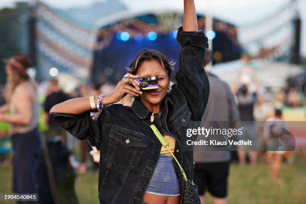 woman photographing through analog camera at festival - denim coat stock pictures, royalty-free photos & images