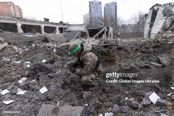 Policeman inspects wreckage near a hole left by a missile in the yard of a damaged residential building after a Russian attack on January 2, 2024 in...