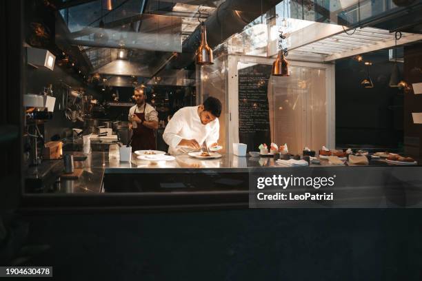 un chef está cocinando en la cocina de su restaurante - cocina comercial fotografías e imágenes de stock