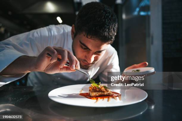 der küchenchef beendet die zubereitung des tellers - kochberuf stock-fotos und bilder
