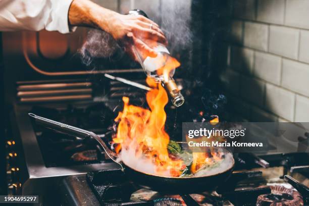 chef frying vegetables with wine in a pan. - chef tossing fire stock-fotos und bilder