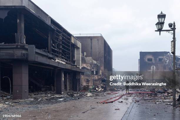 Woman takes a photo near buildings destroyed by fire after earthquakes struck, on January 03, 2024 in Wajima, Japan. A series of major earthquakes...